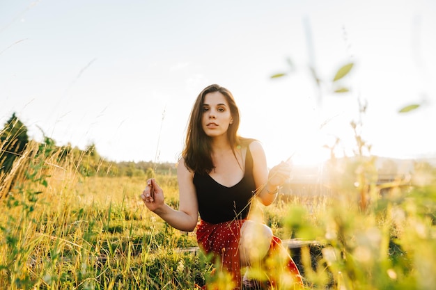 Frau sammelt Blumen auf einem Feld, das für die Kamera posiert