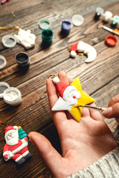 Foto frau schaffen stilvolle weihnachtsgeschenke, malt porzellanfiguren.