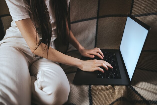 Frau schaut auf einen Laptopbildschirm und tippt auf Tastatur