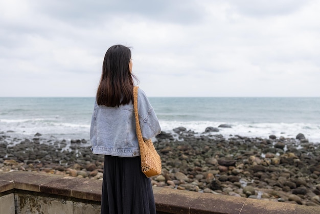 Frau schaut bei nebligem Wetter auf das Meer