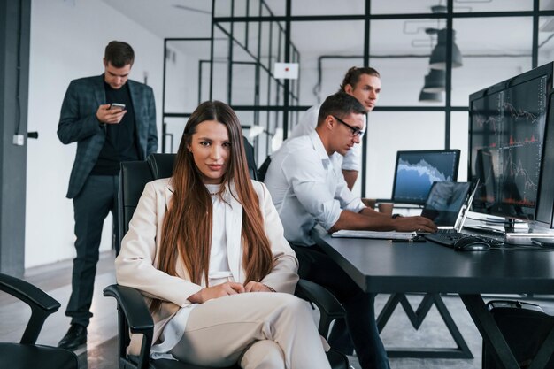 Frau schaut in die Kamera Team von Börsenmaklern arbeitet in modernen Büros mit vielen Bildschirmen