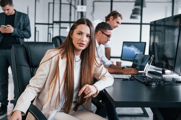 Frau schaut in die Kamera Team von Börsenmaklern arbeitet in modernen Büros mit vielen Bildschirmen