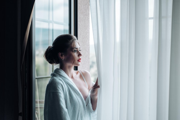 Frau schaut morgens aus dem Fenster