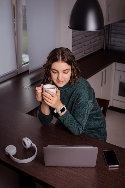 Foto frau schaut sich hilfreiche videos oder tutorials auf dem laptop an, verbessert die balance zwischen arbeit und privatleben, während sie von zu hause aus arbeitet