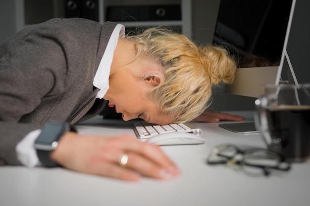 Frau schläft auf der Computertastatur im Büro