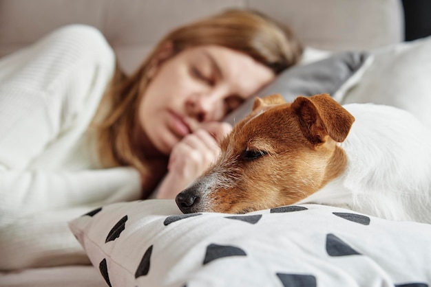 Frau schläft mit Hund auf Sofa