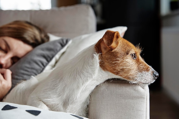 Frau schläft mit Hund auf Sofa