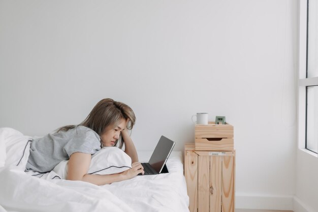 Frau schläft morgens früh im Bett auf dem Tablet-Computer und arbeitet online