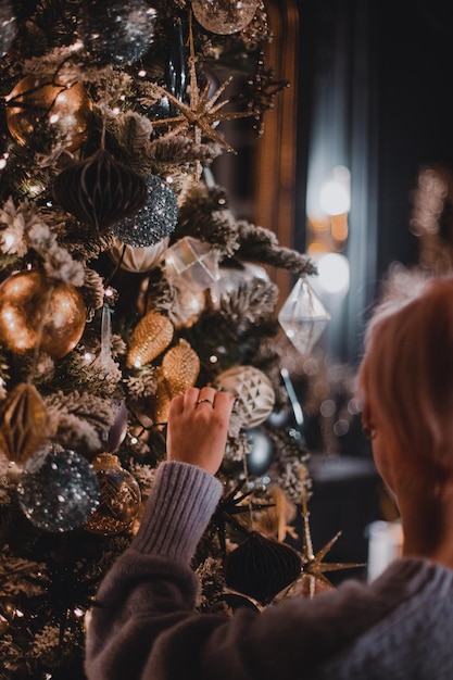 Frau schmückt Weihnachtsbaum mit Spielzeug
