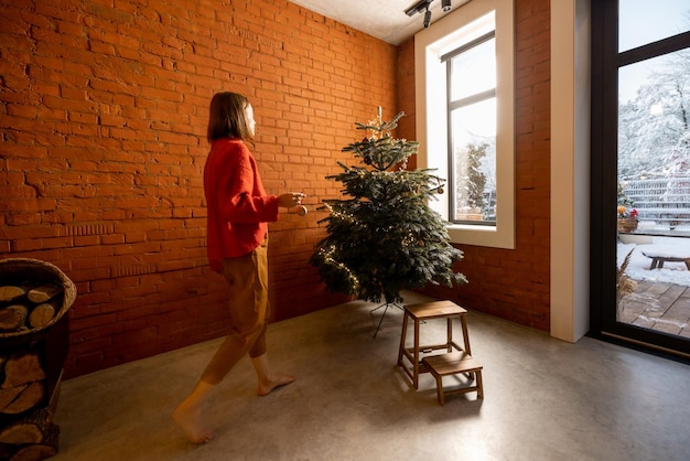 Frau schmückt Weihnachtsbaum zu Hause
