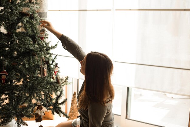 Frau schmückt Weihnachtsbaum zu Hause