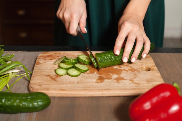 Frau schneidet am Tisch eine Gurke in Ringe