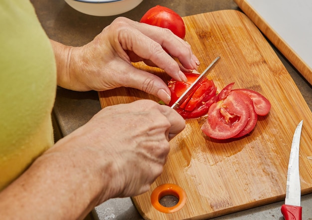 Frau schneidet Tomaten zum Kochen zu Hause nach Rezept aus dem Internet