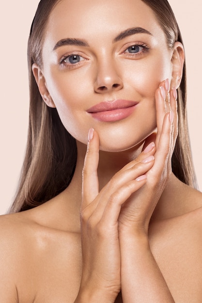 Frau Schönheit gesundes sauberes Haut Make-up junge vorbildliche Hand rührendes Gesicht. Beige Hintergrund.