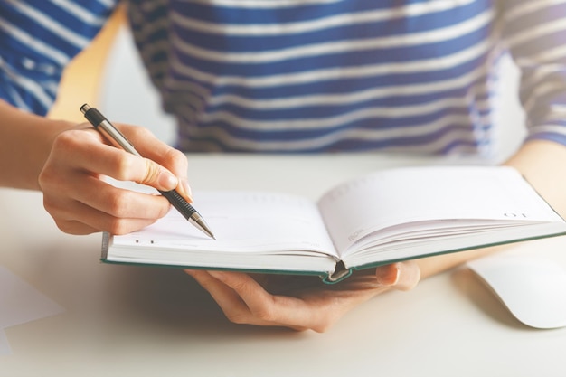 Foto frau schreibt in hardcover-tagebuch