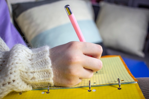 Frau schreibt in Notizbuch mit Bleistift in Großaufnahme