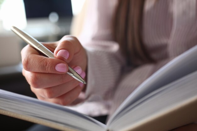 Frau schreibt mit Stift im Notizbuch im Büro oder zu Hause