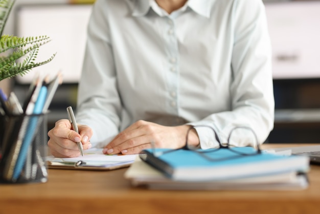 Frau schreibt mit Stift in Dokumenten am Arbeitsplatz
