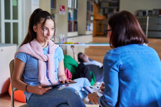 Frau Schulpsychologin Lehrerin spricht und hilft Schülerin Teenager