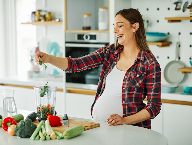 Frau schwanger essen gesund weiblich gemüse schwangerschaft mutter vorbereitung essen zu hause jung salat glücklich mutterschaft gesundheit küche diät grün smoothy