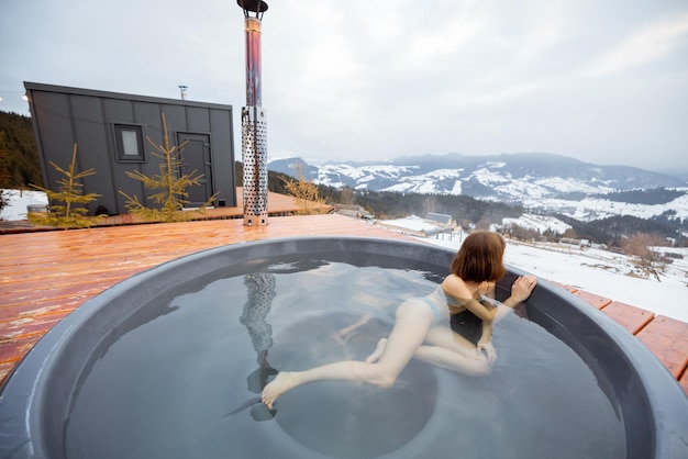 Foto frau schwimmt im heißen bad, während sie sich in einem kleinen modernen haus in den bergen ausruht