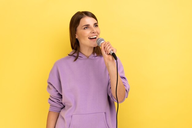 Frau singt laut Lied mit Mikrofon in der Hand und hat Spaß beim Ausruhen im Karaoke-Sänger