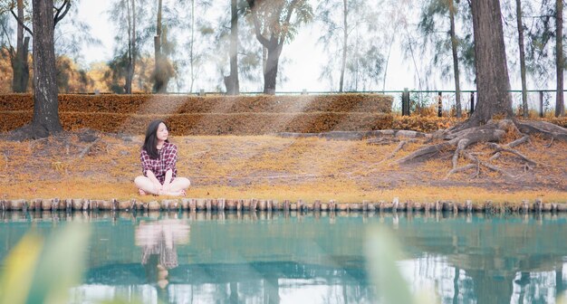 Foto frau sitzt am baumstamm am see