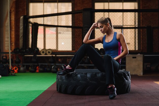 Frau sitzt am Reifen im Fitnessstudio