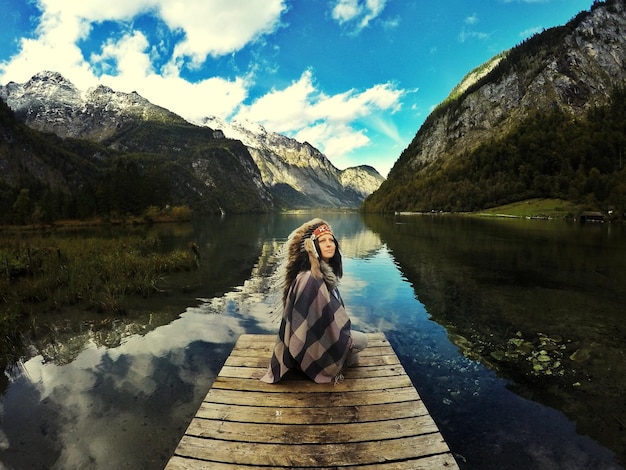 Foto frau sitzt am see auf dem anlegestell