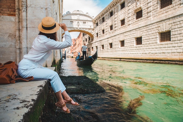Frau sitzt am Stadtkai in Venedig Italien und genießt den Blick auf die Kanäle mit Gondeln