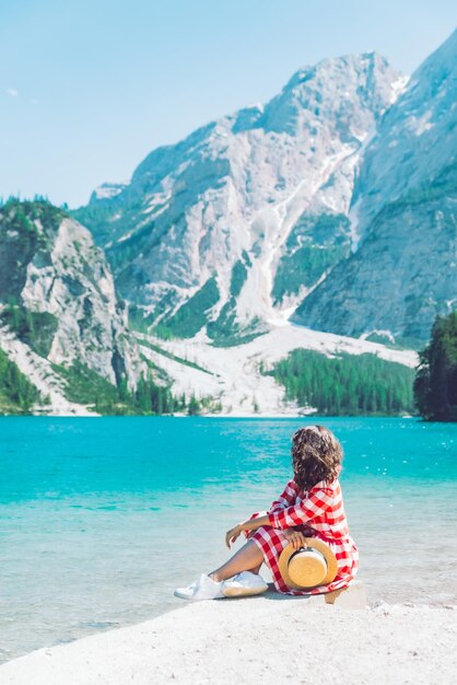 Frau sitzt am Strand eines Bergsees Sommersaison malerische Landschaftsansicht