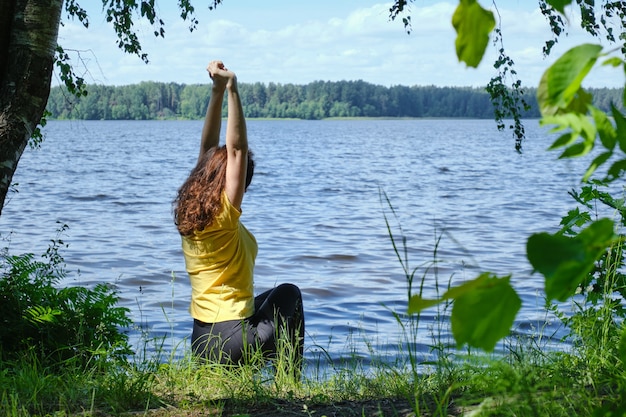 Frau sitzt am Ufer mit See