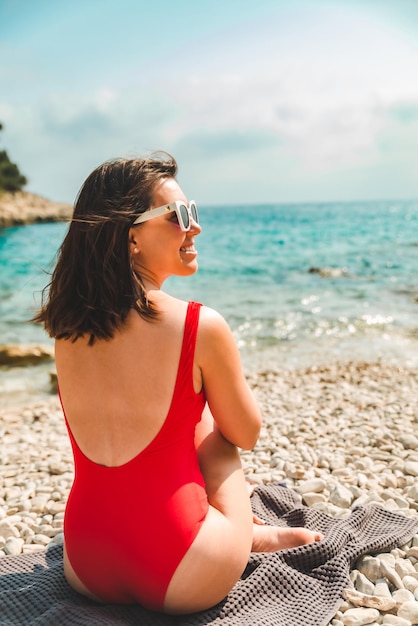 Frau sitzt auf Decke am Strand Sommerurlaub Konzept