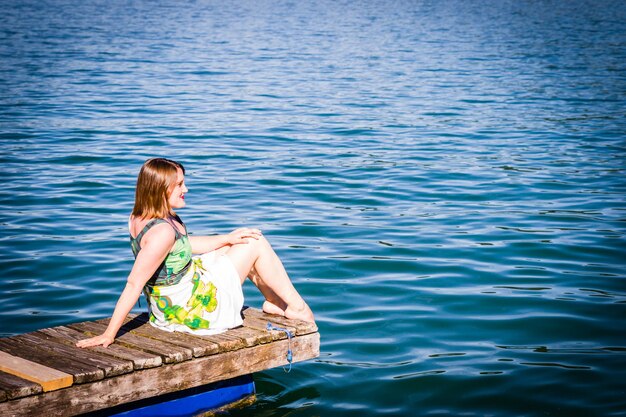 Foto frau sitzt auf dem pier über dem see