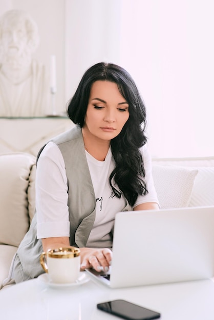 Frau sitzt auf dem Sofa und macht sich Notizen in ihrem Notizbuch Business Analytics Education