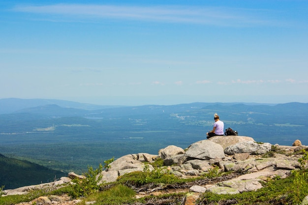 Foto frau sitzt auf einem felsen gegen den himmel