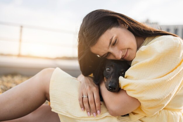 Foto frau sitzt auf einem felsigen pfad und umarmt einen dackelhund