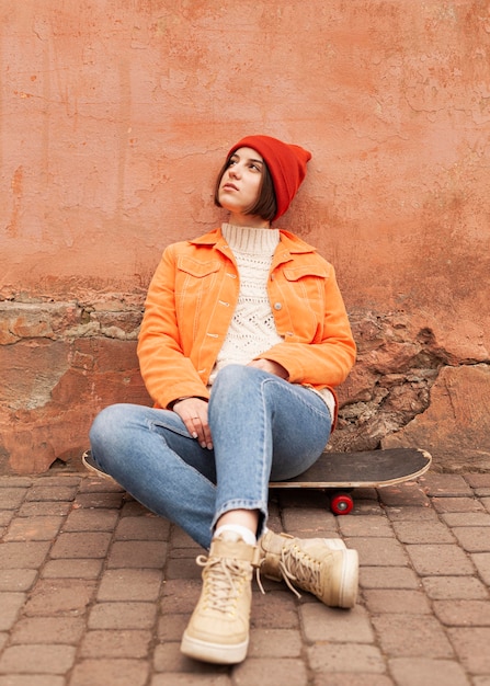 Foto frau sitzt auf einem hölzernen skateboard