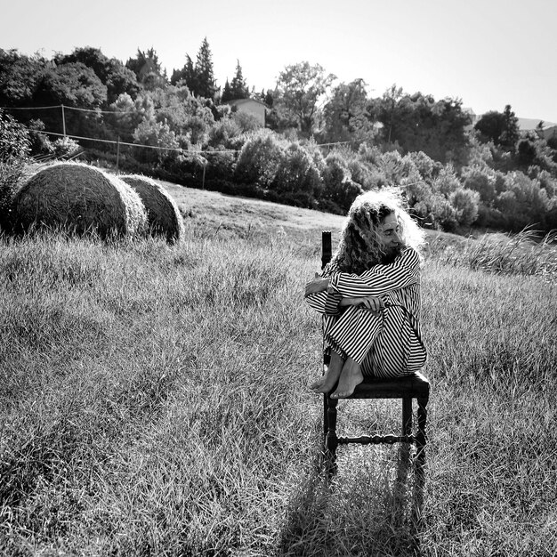 Foto frau sitzt auf einem stuhl auf dem feld