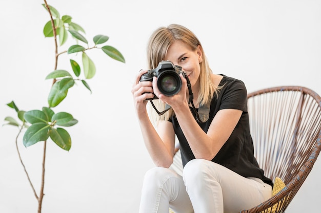 Foto frau sitzt auf einem stuhl neben einer zimmerpflanze