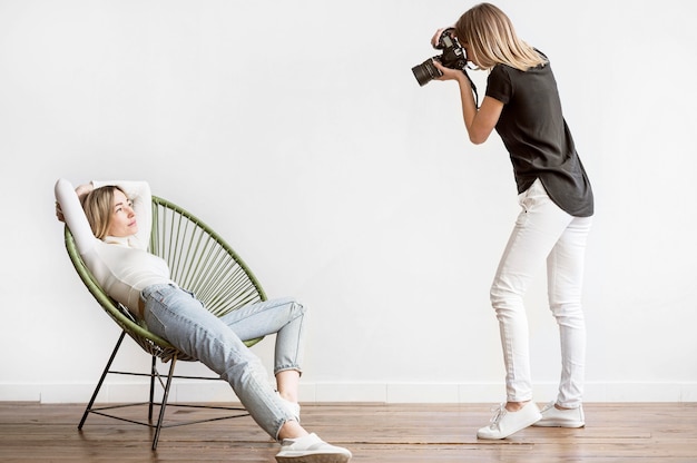 Foto frau sitzt auf einem stuhl und fotograf