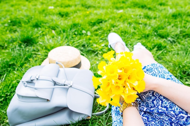 Frau sitzt auf Gras im Stadtpark mit gelben Blumen