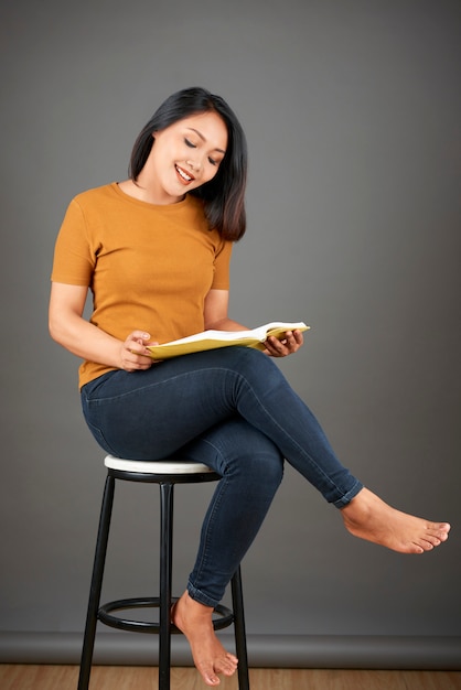 Frau sitzt auf Hocker mit Buch