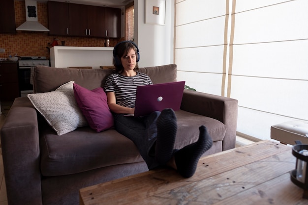 Frau sitzt auf Sofa mit Laptop