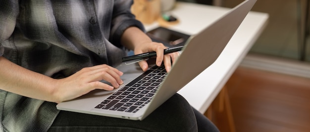 Frau sitzt auf Tisch während der Arbeit am Laptop