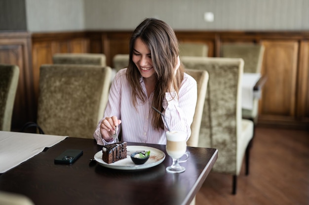 Frau sitzt drinnen im Café-Restaurant und isst Schokoladen-Brownie-Dessertkuchen