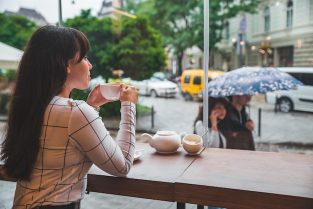 Frau sitzt im Café mit großem Glasfenster und schönem Blick auf die Stadtstraße