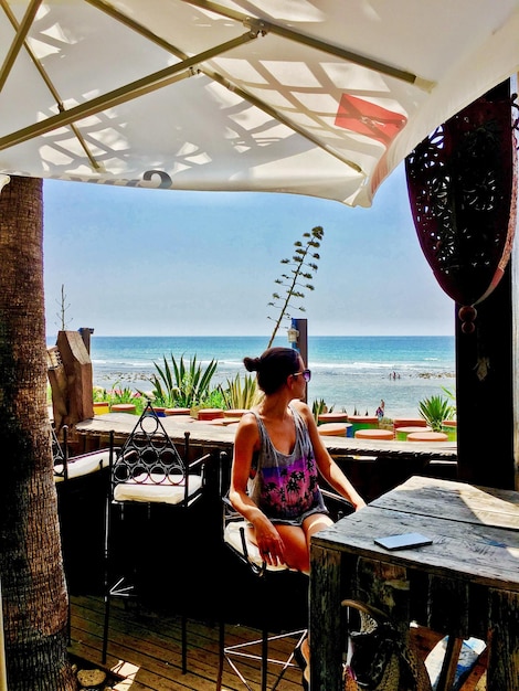 Foto frau sitzt im restaurant am meer