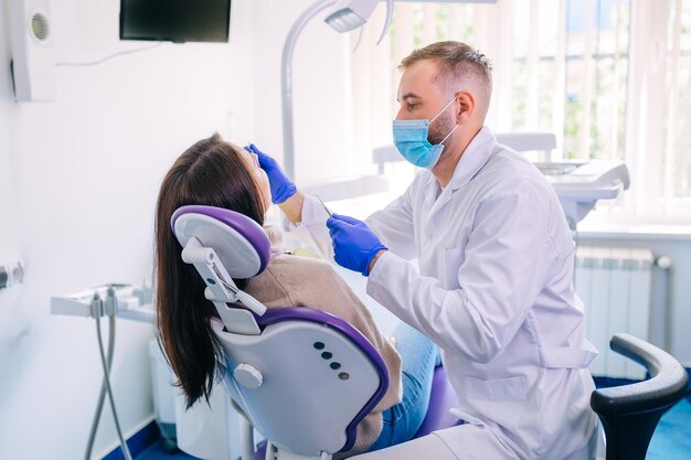 Frau sitzt im Zahnarztstuhl und unterzieht sich einer Zahnarztuntersuchung
