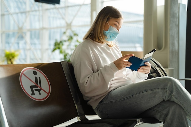 Frau sitzt in der Flughafenlounge und schaut auf ihren Pass